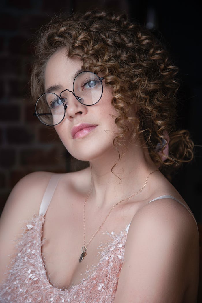 Elegant portrait of a woman wearing eyeglasses and adorned with jewelry, highlighting a modern fashion style.